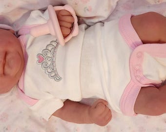 Este adorable bebé despierto es 100 % de silicona suave y está disponible en talla niño, niña o gemelos. Mide 38 cm de largo y pesa 1,4 kg.
