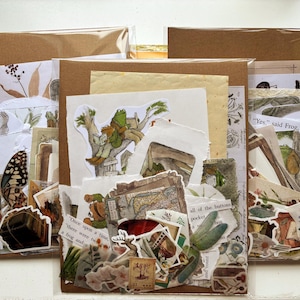 Puede incluir: Tres paquetes de papel kraft llenos de efímeras, pegatinas y trozos de papel. Los paquetes contienen ilustraciones de mariposas, ranas y botánica. El texto incluye "Once upon a time...", "Yes, said Frog" y "all of the buttons".