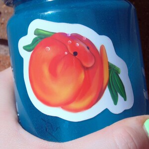 Puede incluir: Una botella de agua de pl&aacute;stico azul con una pegatina de melocot&oacute;n. El melocot&oacute;n es rojo y naranja y tiene una hoja verde.