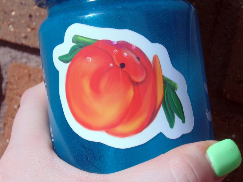 Puede incluir: Una botella de agua de pl&aacute;stico azul con una pegatina de melocot&oacute;n. El melocot&oacute;n es rojo y naranja y tiene una hoja verde.