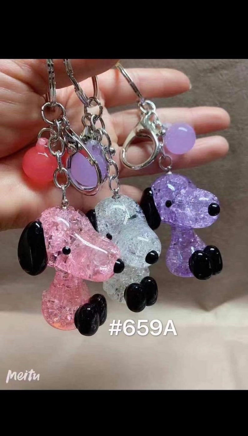 May include: Three sparkly glass dog keychains with black ears and paws. The keychains are pink, white, and purple. The keychains are attached to silver key rings with a small purple, pink, and clear glass bead charm.