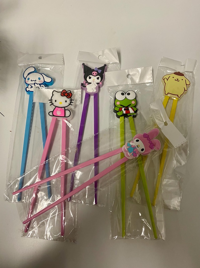 May include: Set of six colourful chopsticks with cartoon character toppers. The toppers include Hello Kitty, My Melody, Keroppi, Cinnamoroll, Kuromi, and Pompompurin.