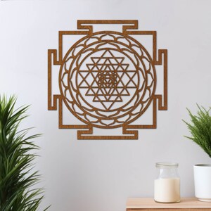 Op de afbeelding: Een bruine houten wanddecoratie met een geometrisch ontwerp. Het ontwerp is een Sri Yantra, een heilig symbool in het hindoe&iuml;sme.
