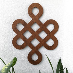 May include: A wooden wall decoration in the shape of a Celtic knot, with a dark brown stain finish.