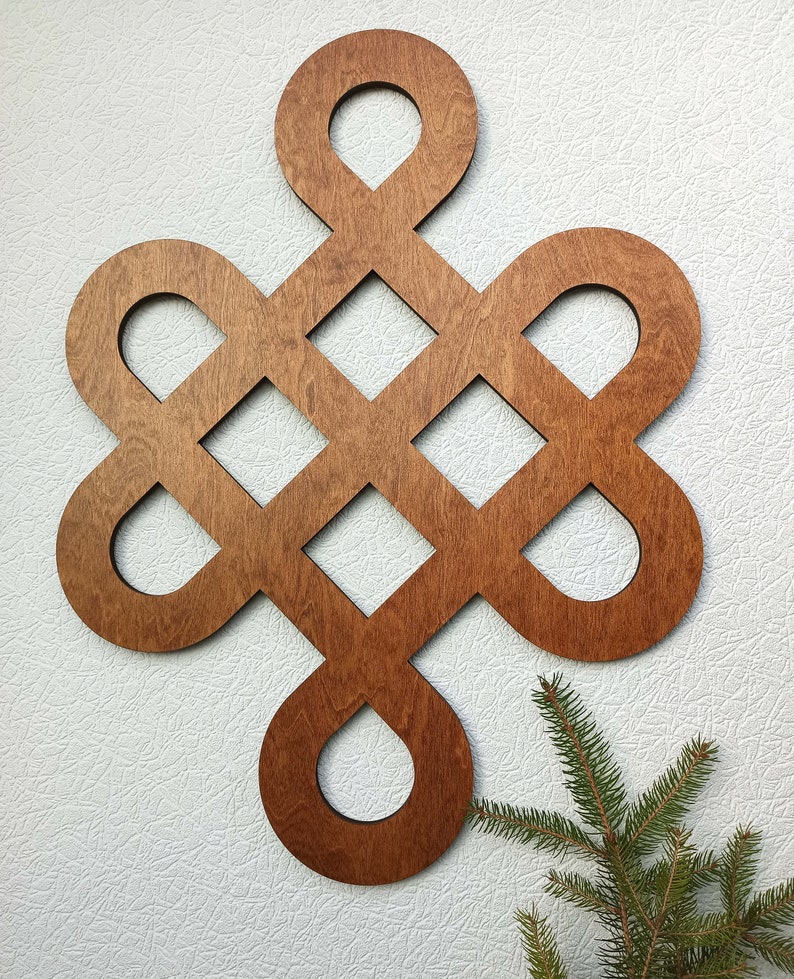 May include: A wooden wall decoration in the shape of a knot, with a brown stain finish. The knot is made of multiple overlapping circles and squares.