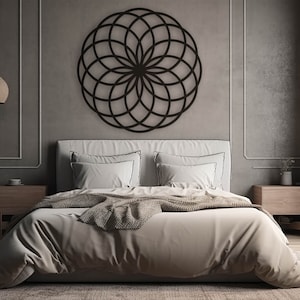 K&ouml;nnte beinhalten: Ein Schlafzimmer mit einer grauen Wand und einem schwarzen geometrischen Wandbild &uuml;ber einem Bett mit wei&szlig;en Bettw&auml;sche und einer braunen Wolldecke. An beiden Seiten des Bettes stehen zwei Nachttische aus Holz.
