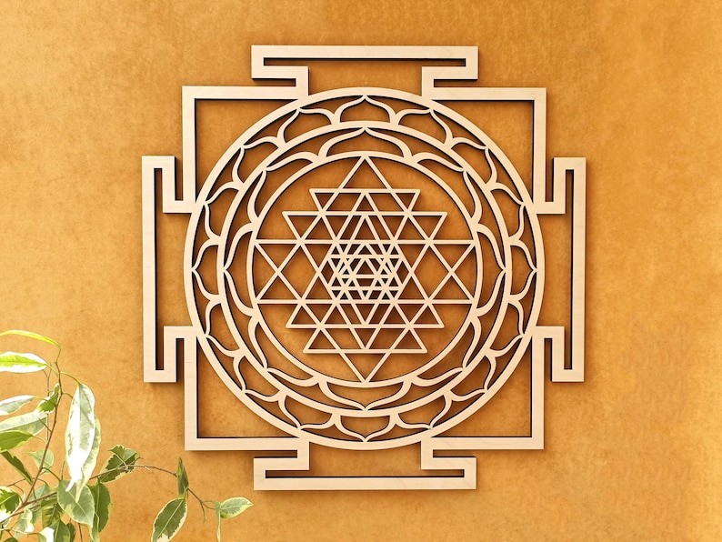 Op de afbeelding: Een houten wanddecoratie met een Sri Yantra, een heilig geometrisch ontwerp in het hindoe&iuml;sme. Het ontwerp is ingewikkeld en gedetailleerd, met meerdere driehoeken en cirkels.