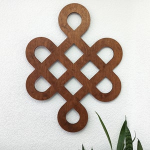 May include: A wooden wall decoration in the shape of a knot, with a brown stain finish. The knot is a traditional symbol of good luck and fortune.