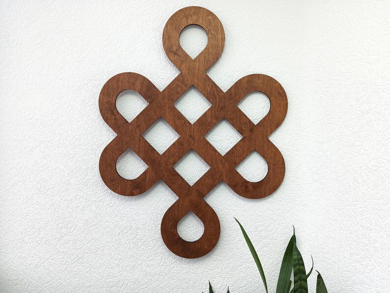 May include: A wooden wall decoration in the shape of a knot, with a brown stain finish. The knot is a traditional symbol of good luck and fortune.