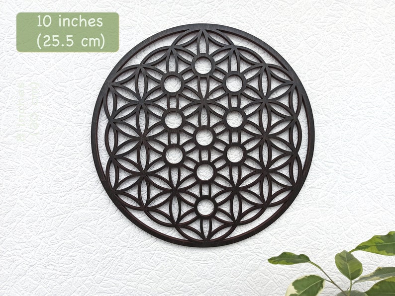 May include: A 10-inch (25.5 cm) wooden wall decor featuring a geometric design known as the Flower of Life. The design is intricate and detailed, with multiple overlapping circles and patterns.