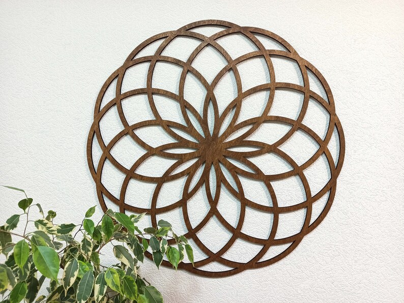 K&ouml;nnte beinhalten: Eine gro&szlig;e, runde Wanddekoration aus Holz mit einem geometrischen Muster. Das Design besteht aus einer Reihe sich &uuml;berlappender Kreise und Linien, die eine komplizierte und symmetrische Mandala-Form bilden.
