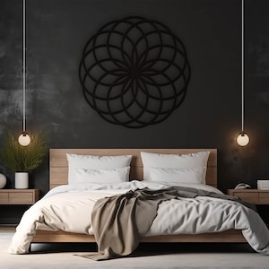 K&ouml;nnte beinhalten: Eine geometrische Wanddekoration in Schwarzwei&szlig; in Form einer Blume h&auml;ngt &uuml;ber einem Bett mit wei&szlig;en Bettw&auml;sche und einer braunen Wolldecke. Zwei Nachttische mit Lampen stehen an beiden Seiten des Bettes.