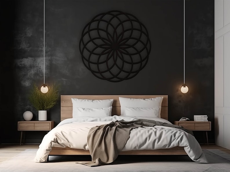 K&ouml;nnte beinhalten: Eine geometrische Wanddekoration in Schwarzwei&szlig; in Form einer Blume h&auml;ngt &uuml;ber einem Bett mit wei&szlig;en Bettw&auml;sche und einer braunen Wolldecke. Zwei Nachttische mit Lampen stehen an beiden Seiten des Bettes.