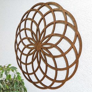 K&ouml;nnte beinhalten: Eine braune Holz-Wanddekoration mit einem geometrischen Design. Das Design ist ein Kreis mit einer Reihe konzentrischer Kreise und Linien, die vom Zentrum ausstrahlen.