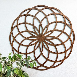 K&ouml;nnte beinhalten: Eine gro&szlig;e, h&ouml;lzerne Wanddekoration in Form eines Mandalas mit komplizierten geometrischen Mustern. Das Mandala ist braun und hat eine kreisf&ouml;rmige Form.