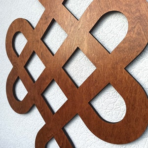 May include: A wooden wall decoration in the shape of a knot, with a dark brown stain finish.