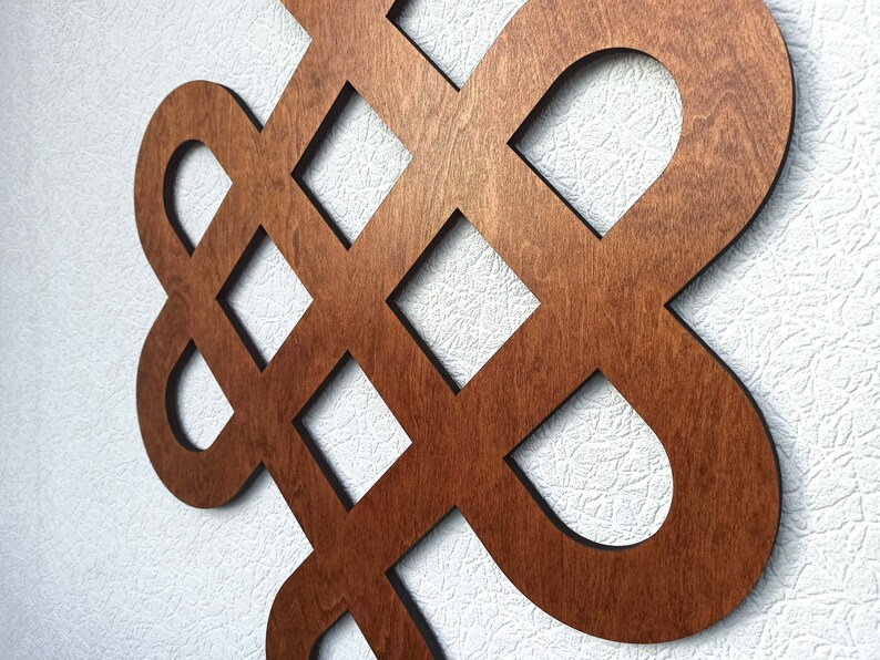 May include: A wooden wall decoration in the shape of a knot, with a dark brown stain finish.