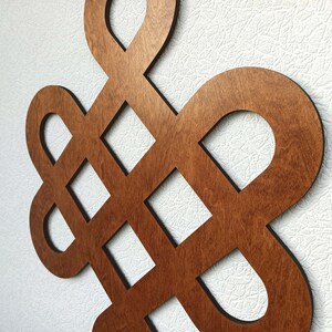 May include: A brown wooden wall decoration in the shape of a knot. The knot is a traditional symbol of good luck and fortune.