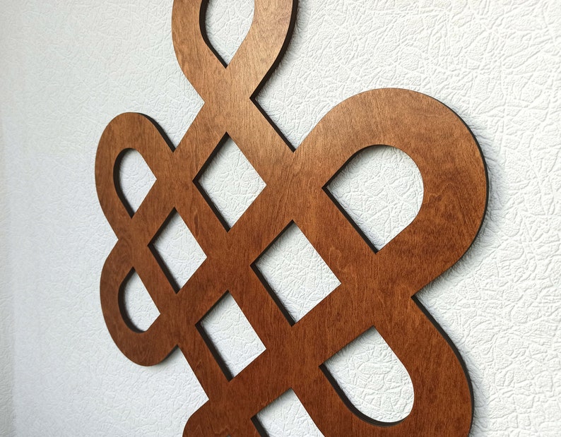 May include: A brown wooden wall decoration in the shape of a knot. The knot is a traditional symbol of good luck and fortune.