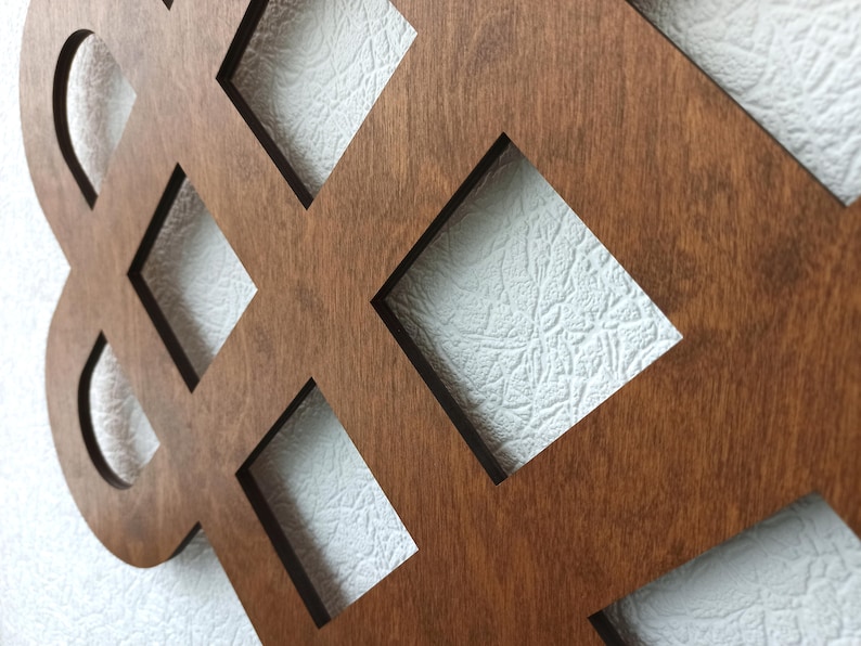 May include: A brown wooden wall decoration with a geometric design featuring a repeating pattern of squares and circles. The design is reminiscent of a Celtic knot.