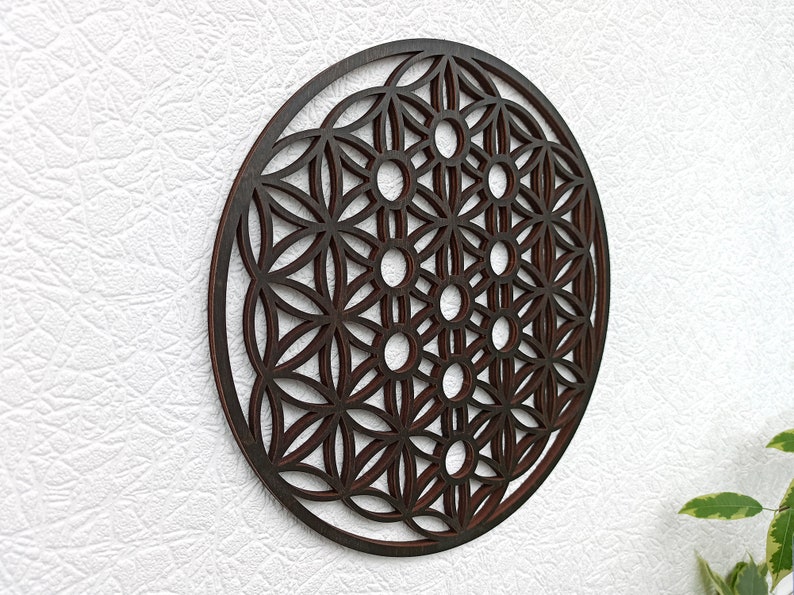 May include: A dark brown wooden wall hanging with a geometric pattern, resembling a flower of life mandala.