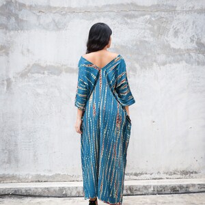 May include: A long, blue and brown tie-dye maxi dress with a V-neckline and 3/4 sleeves. The dress has a loose, flowing fit and is perfect for a casual summer look.