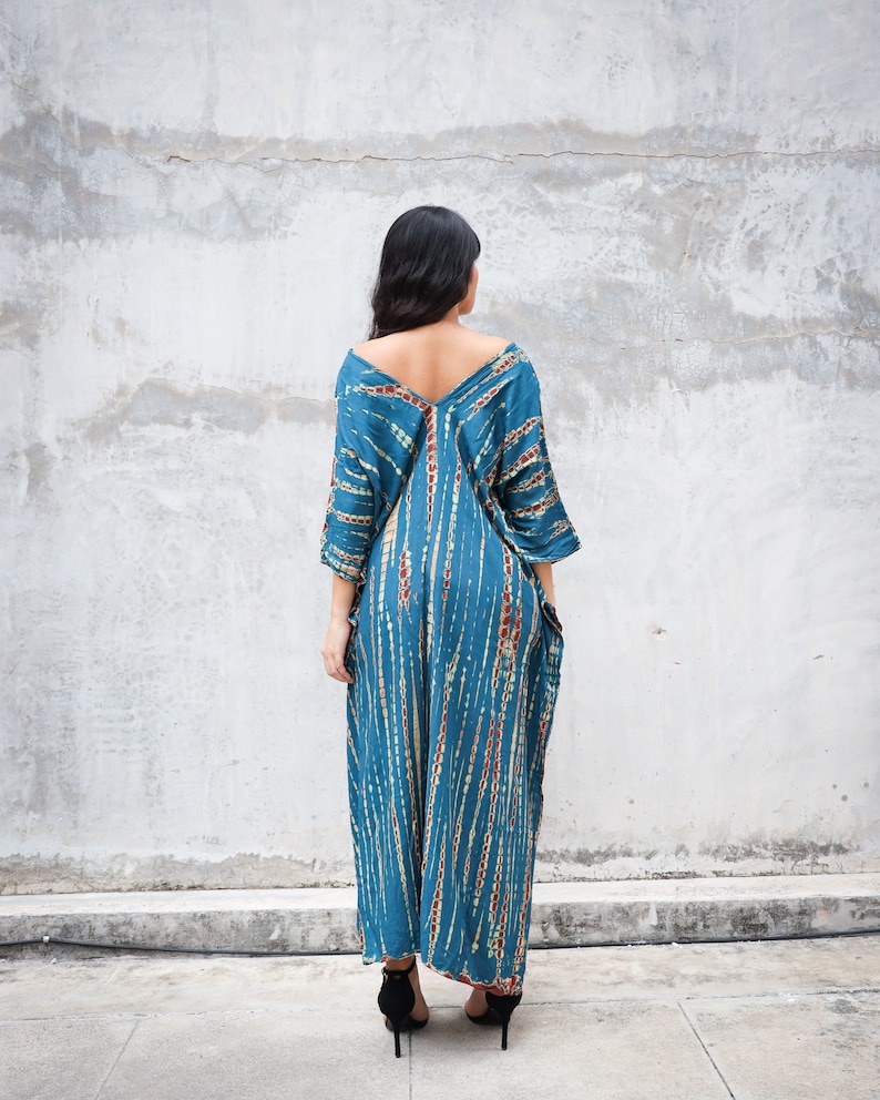 May include: A long, blue and brown tie-dye maxi dress with a V-neckline and 3/4 sleeves. The dress has a loose, flowing fit and is perfect for a casual summer look.