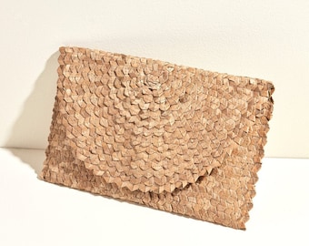 Könnte beinhalten: Eine hellbraune Clutch mit einem einzigartigen geometrischen Muster. Die Clutch besteht aus gewebtem Material mit einem Klappenverschluss. Die Textur des Materials ist sichtbar, und das Gesamtdesign ist natürlich und erdig.