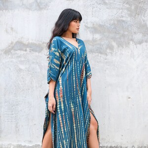 May include: A long, blue and brown tie-dye maxi dress with a V-neck and side slits.