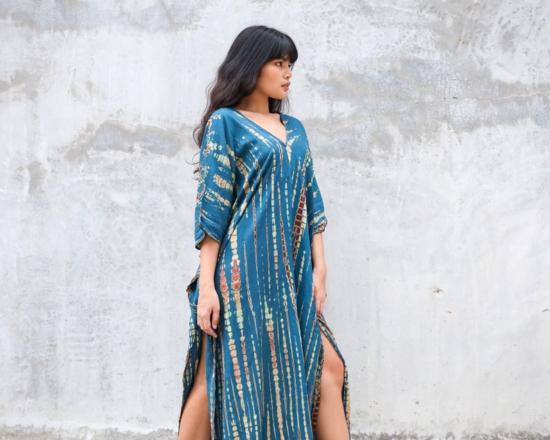 May include: A long, blue and brown tie-dye maxi dress with a V-neck and side slits.