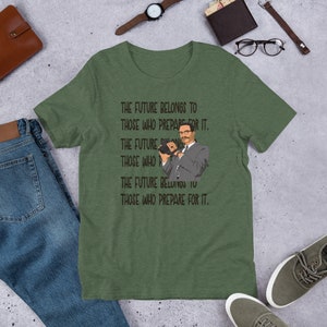 Puede incluir: Una camiseta verde con un gr&aacute;fico negro de un hombre sosteniendo una c&aacute;mara. El texto en la camiseta dice "The future belongs to those who prepare for it."