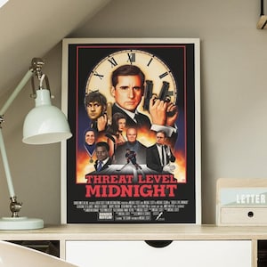 May include: A framed poster featuring the movie "Threat Level Midnight." The poster has a black background with a clock face and several characters. The title is in red letters. The Dunder Mifflin logo is at the bottom.