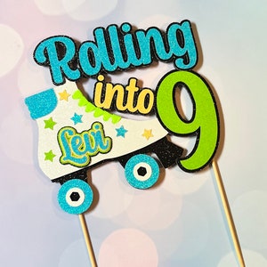 May include: A white roller skate with blue and green glitter accents. The skate has the name "Levi" written on it and the words "Rolling into 9" above it. The number 9 is green with glitter.