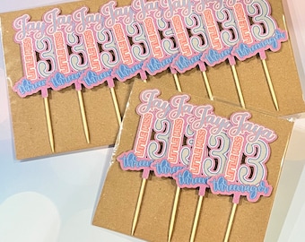 May include: A set of 10 pink and blue cupcake toppers with the text "Jay Jay Jaya Little Miss 33" and "three-three-three-teenager".