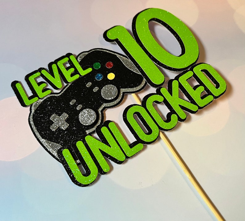 K&ouml;nnte beinhalten: Gr&uuml;ner und schwarzer Tortendekor mit einem Videospiel-Controller und dem Text "Level 10 freigeschaltet".