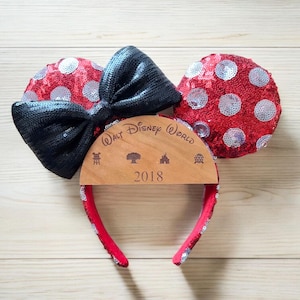 Può includere: Fascia per capelli con orecchie di Minnie Mouse a pois rossi e bianchi, con un fiocco nero e un cartello di legno con la scritta "Walt Disney World 2018".