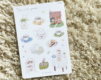 May include: A sheet of stickers with a whimsical tea party theme. The stickers feature a teapot, teacups, a cottage, a tiered cake stand, a rabbit, and the text "Tea in the garden".