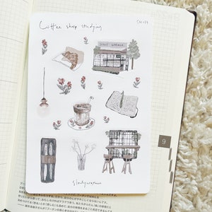 May include: A set of nine illustrated stickers featuring a coffee shop theme. The stickers include a coffee shop storefront, a cup of coffee, a book, a pair of scissors, a vase with flowers, a light fixture, and two chairs. The stickers are in a watercolor style with a light brown and beige color palette.