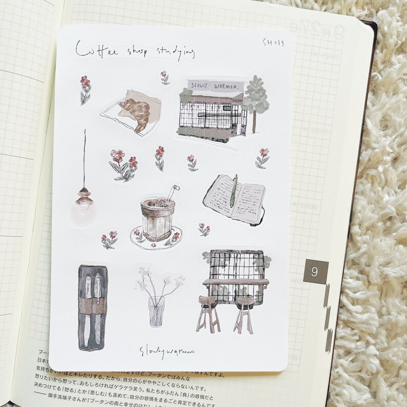 May include: A set of nine illustrated stickers featuring a coffee shop theme. The stickers include a coffee shop storefront, a cup of coffee, a book, a pair of scissors, a vase with flowers, a light fixture, and two chairs. The stickers are in a watercolor style with a light brown and beige color palette.