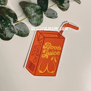 May include: Orange sticker in the shape of a juice box with the words "Boob Juice" in a retro font. The sticker also has the words "100% Organic" and a graphic of breasts. A red straw is attached to the top.
