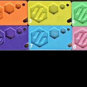 May include: Nine plastic keyrings in different colours, including red, orange, yellow, green, blue, purple, light blue, pink, and white. Each keyring features a hexagonal design with the letters "HG" inside.