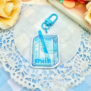 May include: A blue milk carton keychain with a straw and the word 