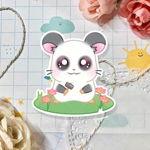 May include: A cartoon hamster with black ears and a white body is holding a small hammer. The hamster is sitting on a green patch of grass with pink flowers. The background is a light blue and white checkered pattern.