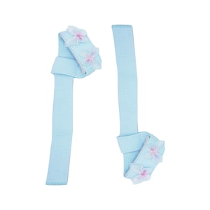 Puede incluir: Dos correas de tela azul claro, cada una con una sección anudada adornada con detalles de mariposas rosas y blancas bordadas. Las correas se muestran sobre un fondo blanco.