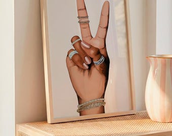 May include: A framed wall art print featuring a brown-toned illustration of a hand making a peace sign. The hand is adorned with multiple silver-toned rings on the fingers and a layered silver-toned bracelet on the wrist, set against a light background.