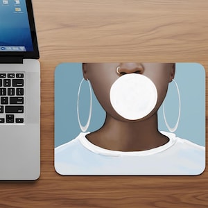 May include: A mousepad featuring a digital illustration of a person with dark skin blowing a large bubble of bubblegum. The person is wearing large silver hoop earrings, a nose ring, and a white t-shirt. The background is a light blue.