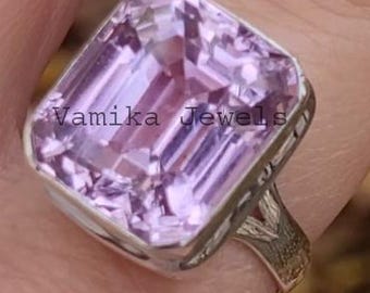May include: A statement ring featuring a large, rectangular-cut, pale purple gemstone. The ring has a silver band with an intricate, textured design. The gemstone is set in a silver bezel. The ring is labelled "Vamika Jewels".