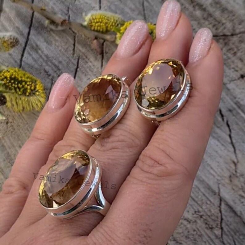 Puede incluir: Un conjunto de dos anillos de plata con piedras preciosas de topacio de forma ovalada. Los anillos est&aacute;n engastados con un engaste de bisel y tienen un acabado pulido. Las piedras preciosas son de color marr&oacute;n claro.