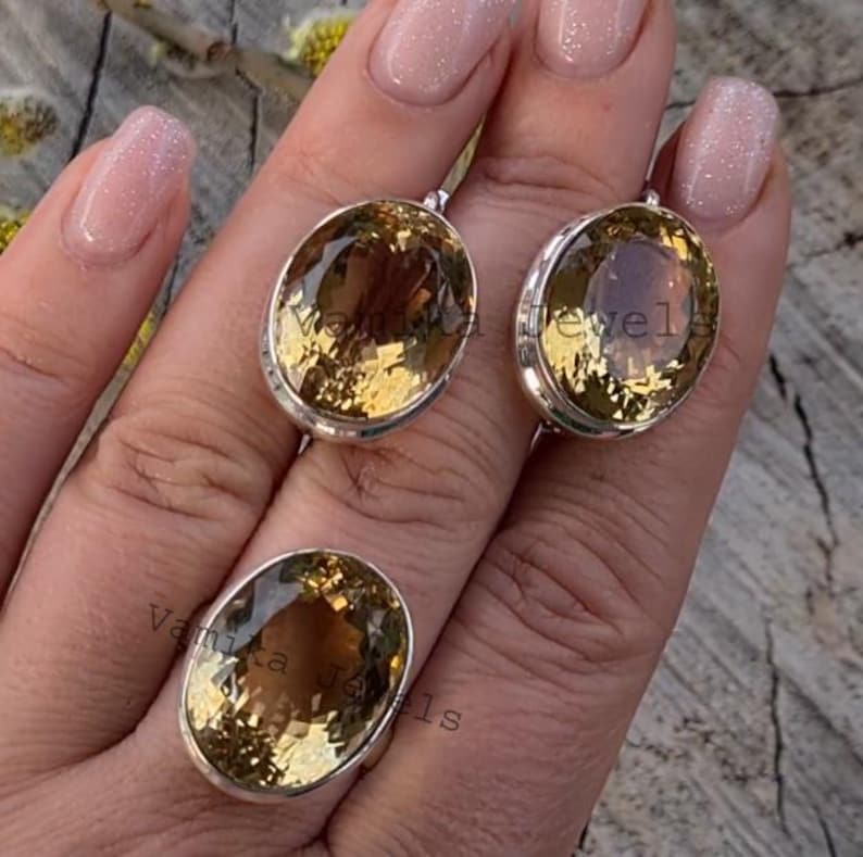 Puede incluir: Un conjunto de tres anillos de plata con piedras preciosas de topacio de forma ovalada. Los anillos est&aacute;n en una mano con u&ntilde;as cuidadas.