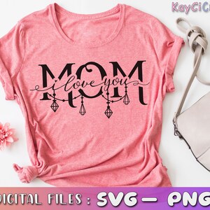May include: Pink t-shirt with the text "MOM I love you" in black lettering with a string of decorative diamonds hanging from the letters.